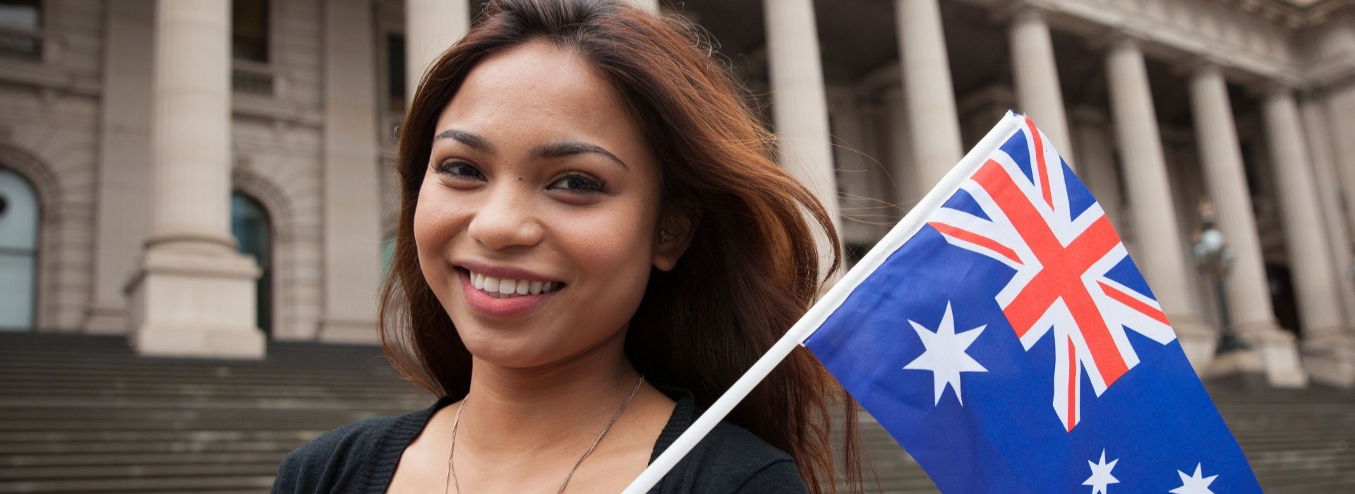 Smiling woman holding Australian flag – Australia PR and Skilled Migration 2025