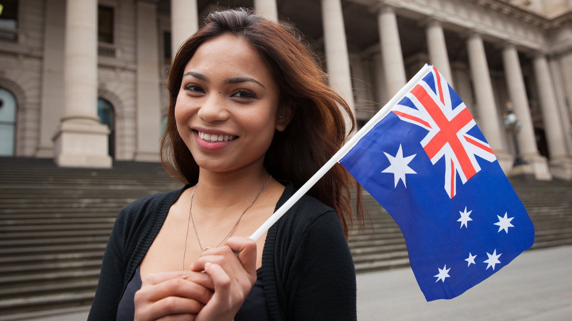 Smiling woman holding Australian flag – Australia Skilled Migration and Work Visa 2025