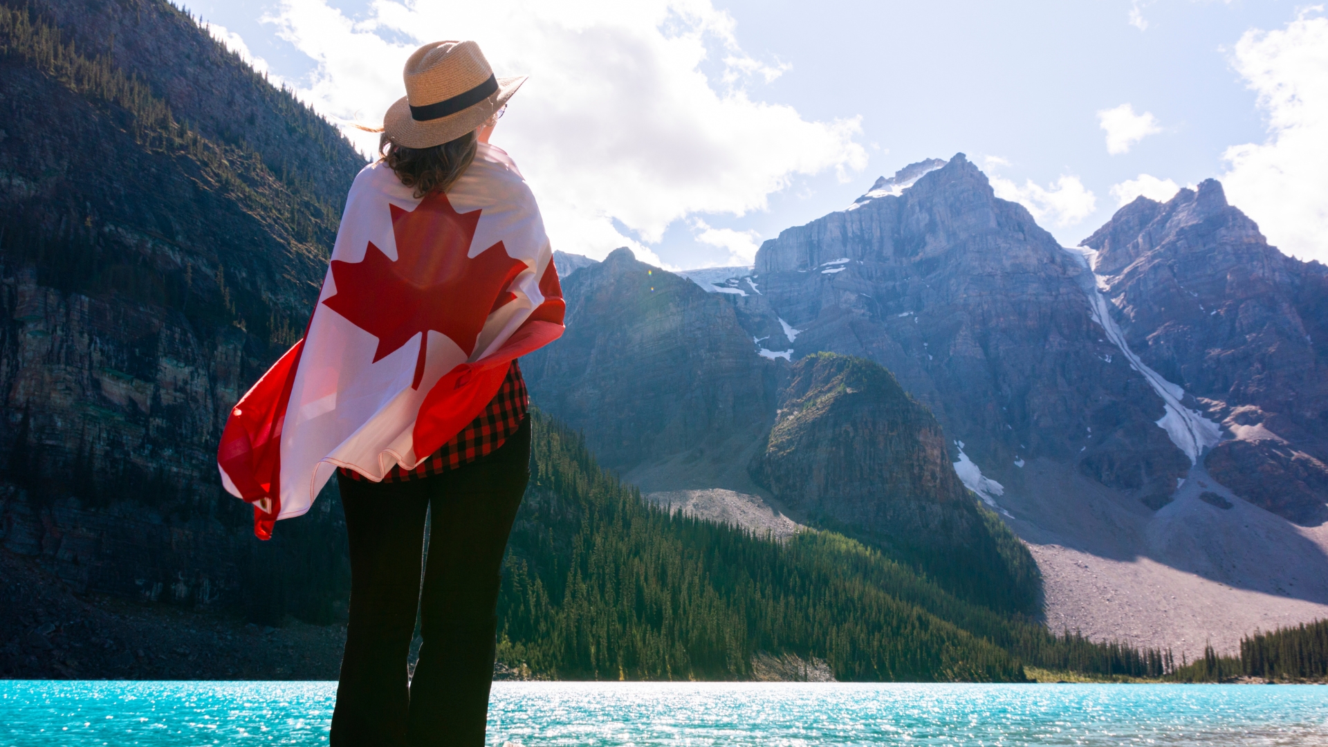 Person wrapped in Canadian flag overlooking mountains – Canada Express Entry 2025
